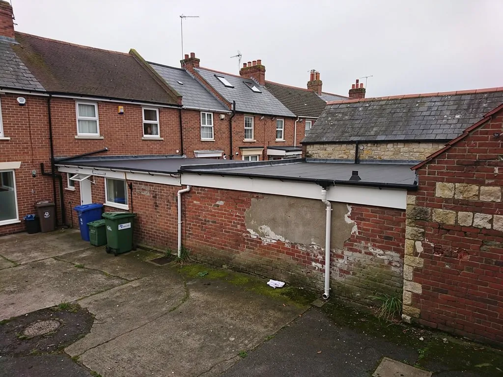 Rear flat roofs of a brick shop parade with flats above