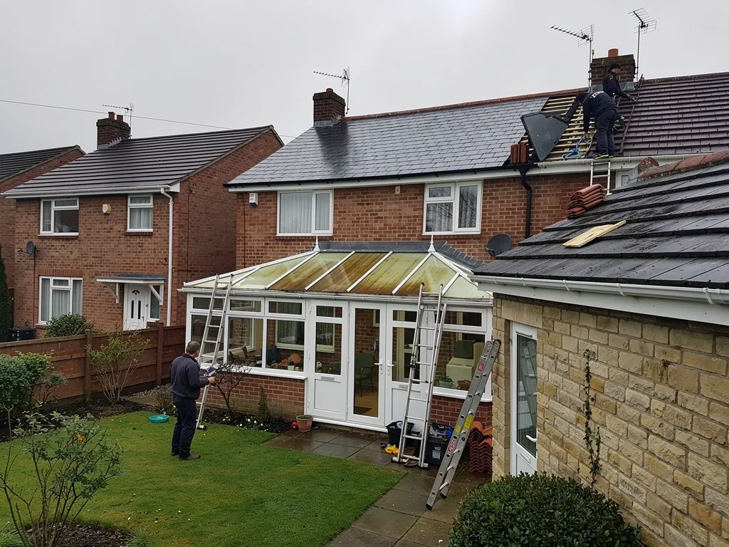 Old conservatory behind a brick semi with roofers working above