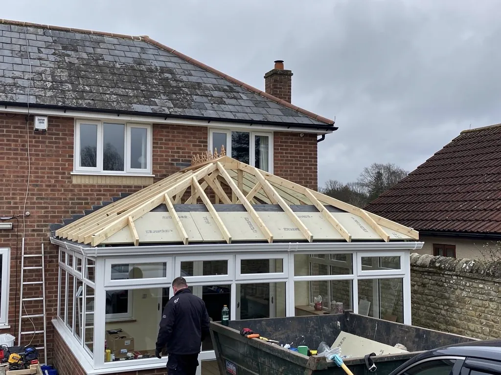 New timber rafters framing a solid roof over a conservatory