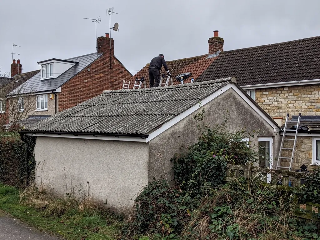 Old corrugated sheet roof on a rendered garage beside houses