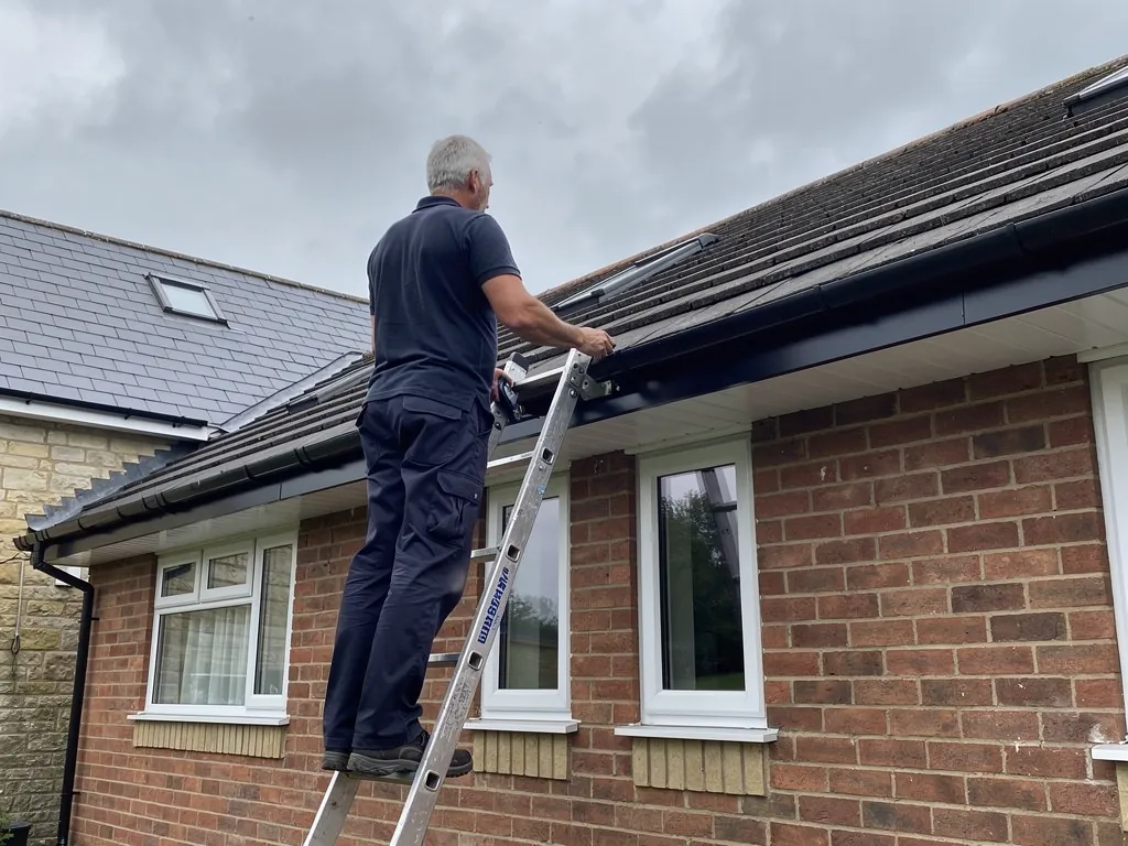 Roofer fitting new anthracite gutter to a uPVC fascia