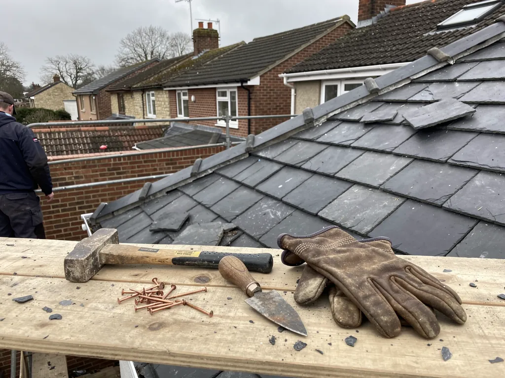 Roofer's hammer, nails, trowel and gloves on a scaffold board
