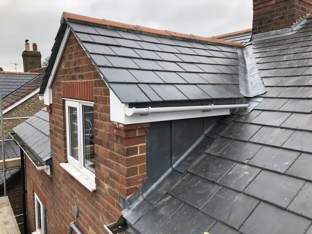 Lead apron flashing below a brick dormer on a slate roof