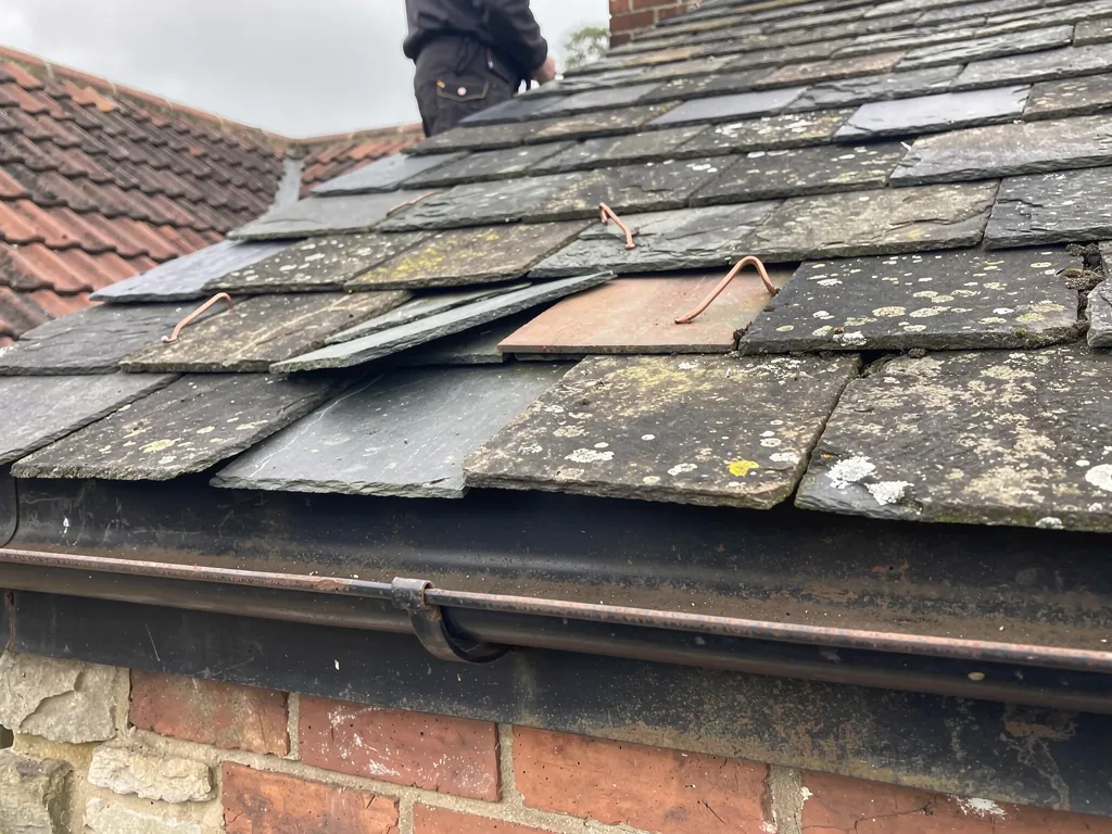 Replacement slates held with copper tingles on an older slate roof