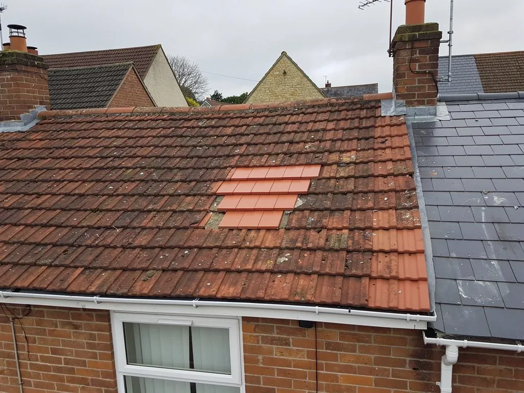 Patch of newly replaced clay tiles on a weathered terrace roof