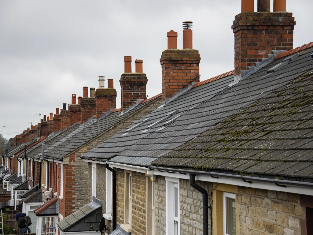 Row of Victorian terrace slate roofs with brick chimney stacks