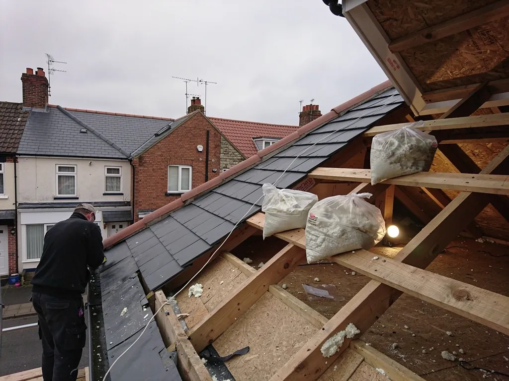 Opened roof with bags of removed spray foam on rafters