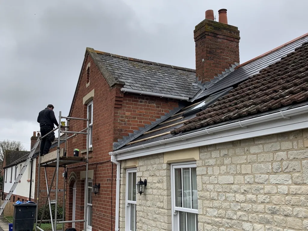 Brick end-of-terrace gable beside a limestone house, slate roofs