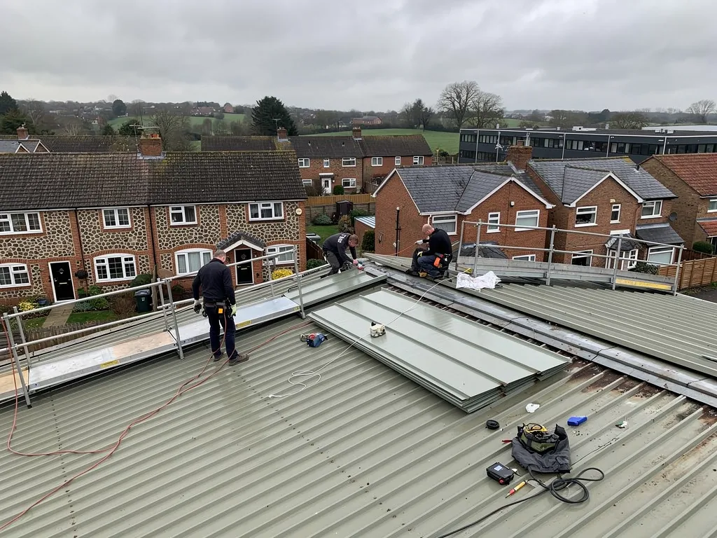 Roofers fitting profiled metal sheets on a commercial unit roof
