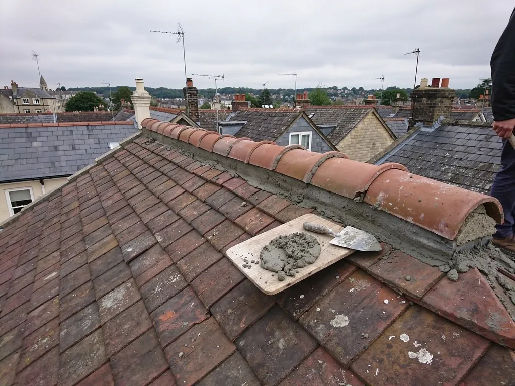 Freshly mortared clay ridge tiles with trowel and mortar board
