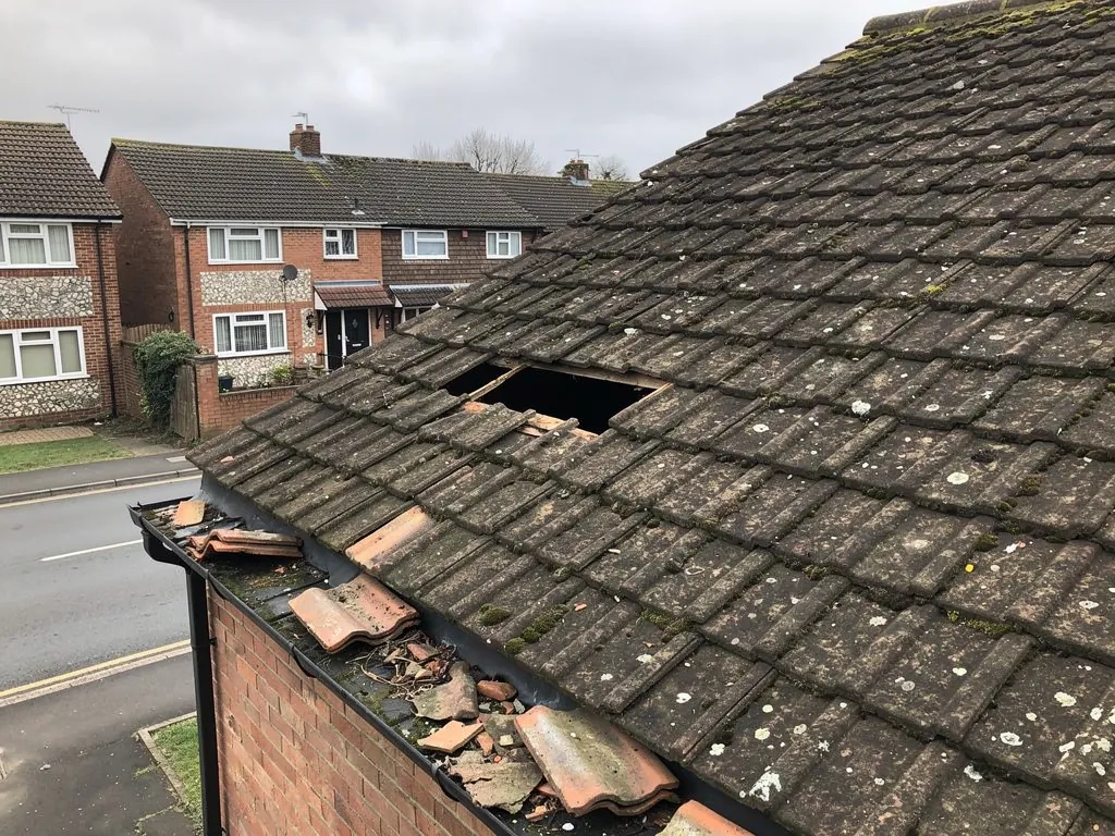 Missing and broken concrete tiles on a roof above the gutter