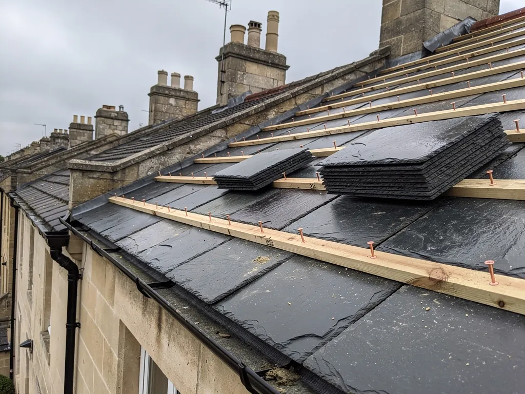 New slates stacked on battens during a terrace re-slate