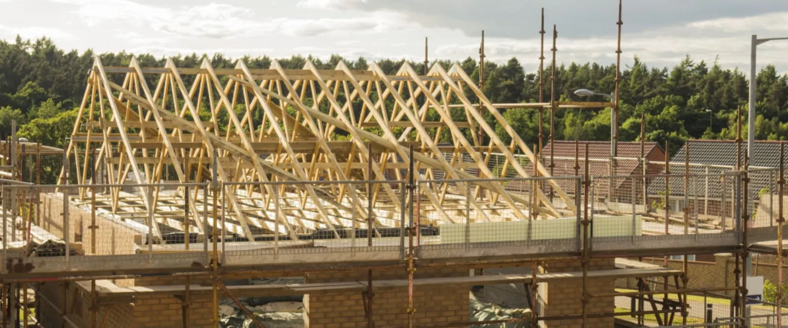 Timber roof trusses on a new brick house behind scaffolding
